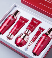 Facial care cosmetics set with six red and silver skincare bottles and tubes in a white box