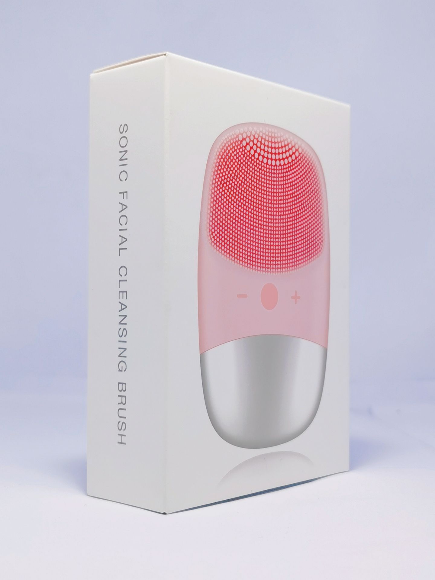 Electric silicone face cleansing brush in pink and silver shown on white product packaging box
