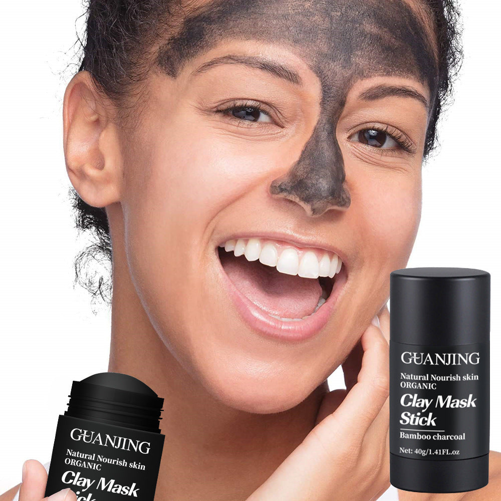 Smiling woman applying organic bamboo charcoal face mask with GuanJing clay mask stick