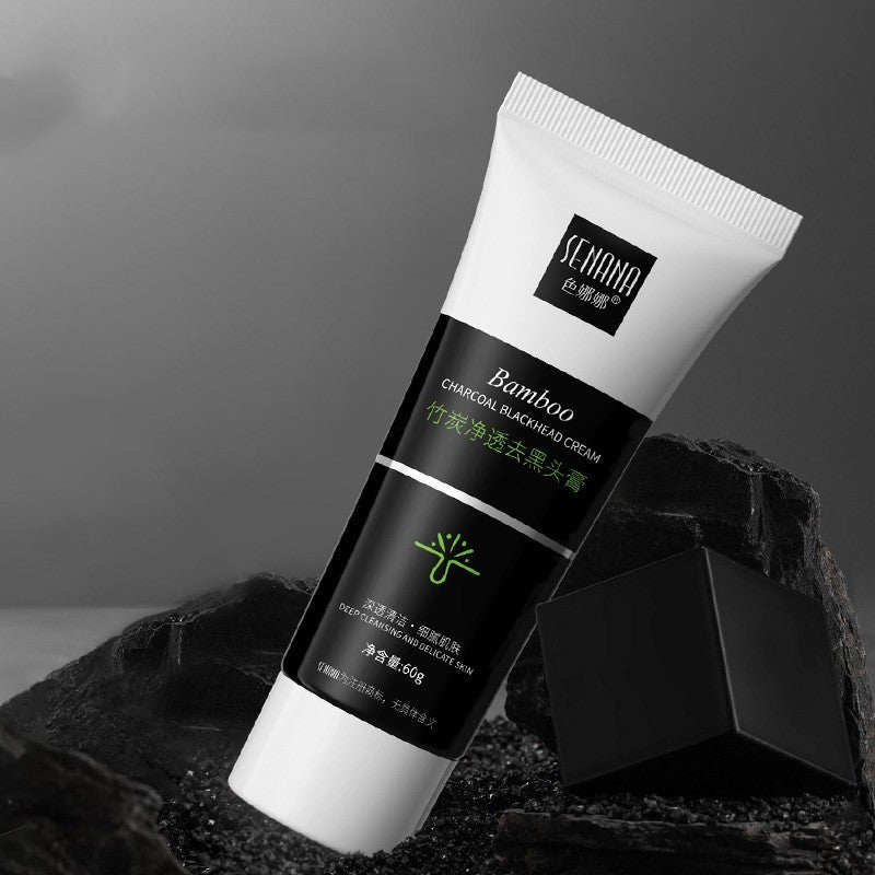 Tube of bamboo charcoal blackhead remover cream with black and white packaging on natural black charcoal background