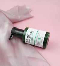 Bye Bye Blackhead green tea facial cleanser in green pump bottle on pink fabric background