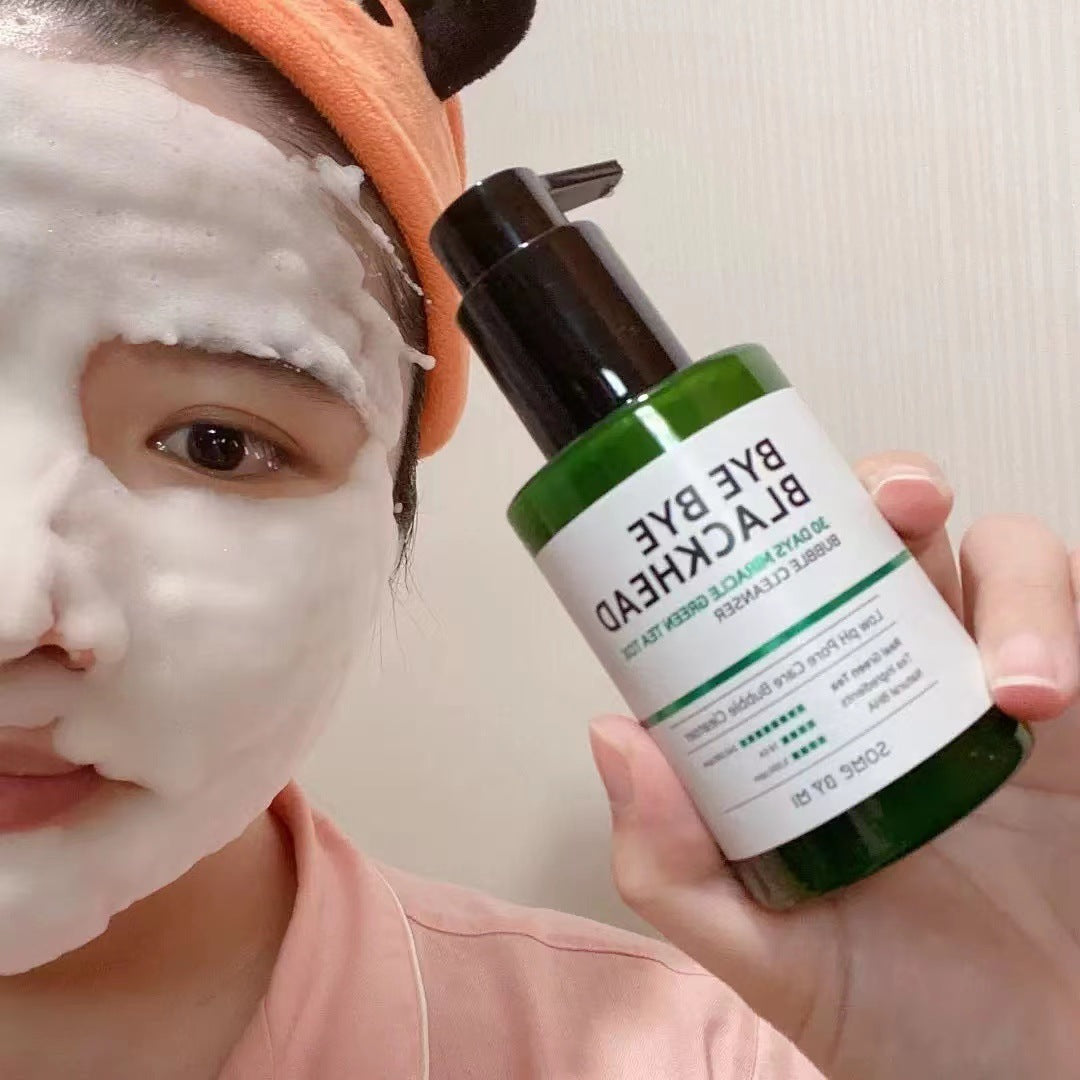 Person applying green tea facial cleanser with foam on face holding green bottle with black pump