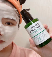 Person applying green tea facial cleanser with foam on face holding green bottle with black pump