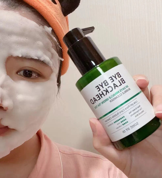 Person applying green tea facial cleanser with foam on face holding green bottle with black pump