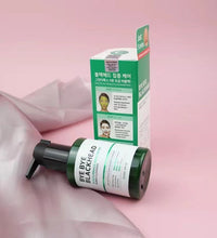 Green tea facial cleanser bottle with pump and matching green and white box on pink background